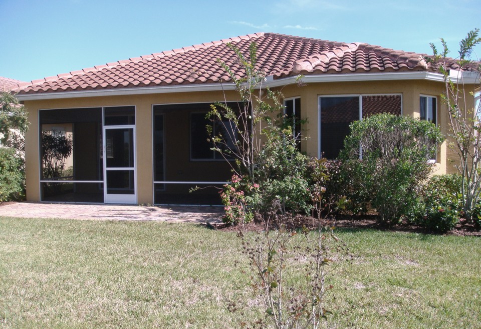 back of home with screened patio and added patio