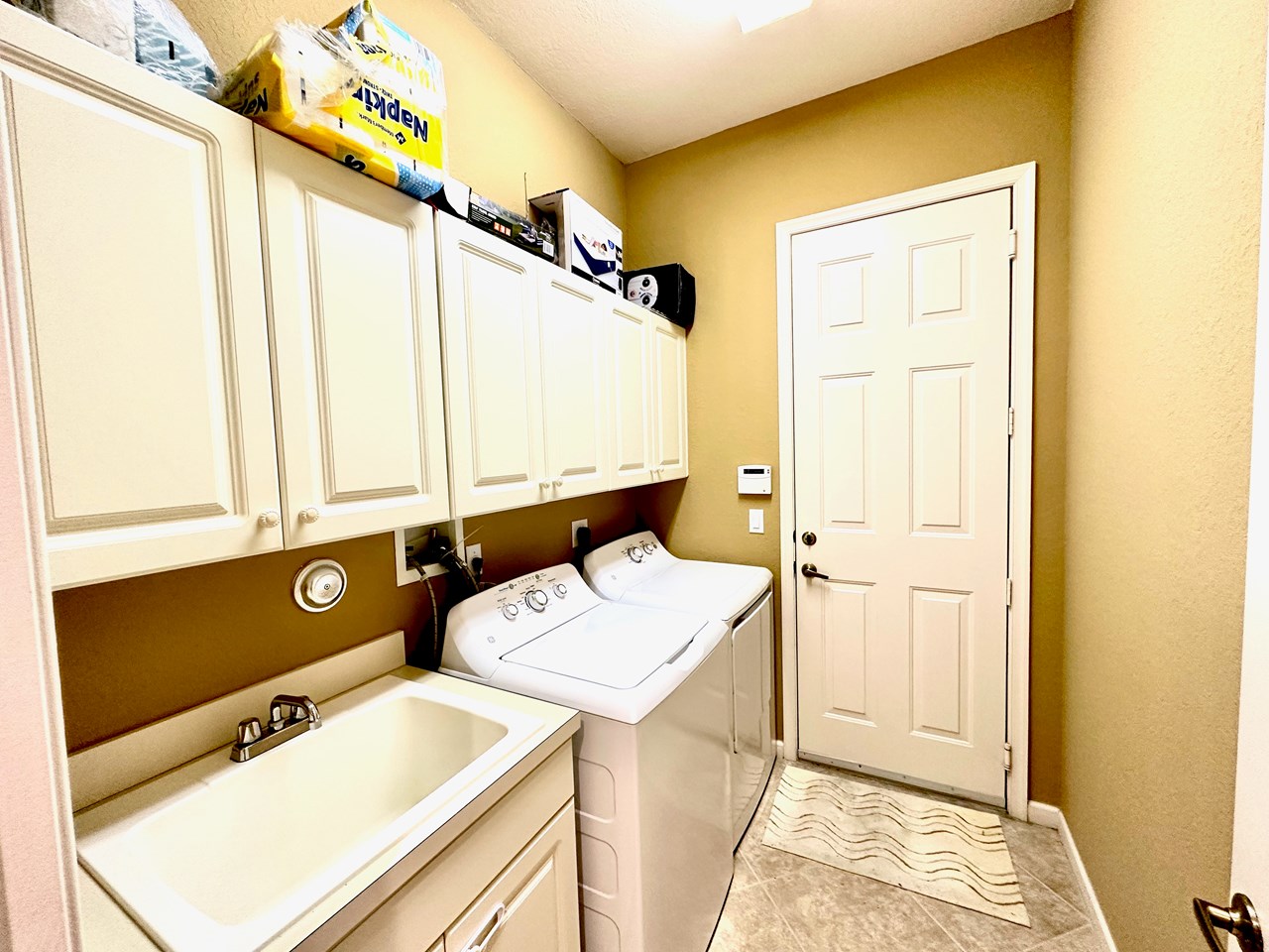 laundry room with utility sink, washer/dryer and cabinets