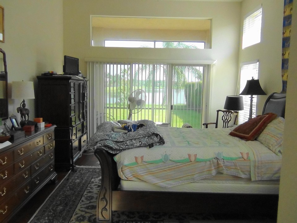 master bedroom, with tray ceiling, wood-like flooring & view of lake